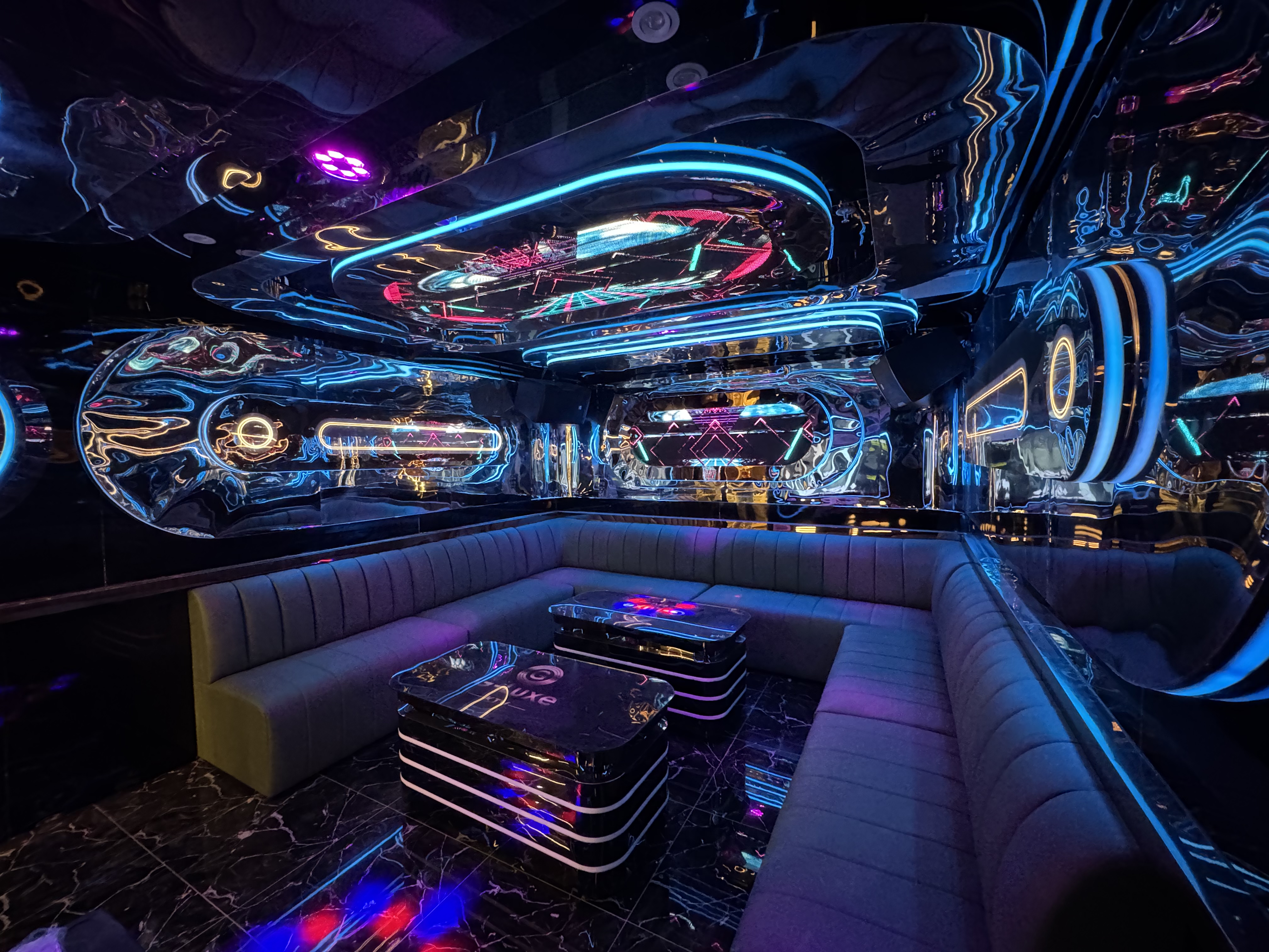 The opulent interior of a Taiwanese nightclub, featuring a sleek gray couch and matching table adorned with vibrant neon l...