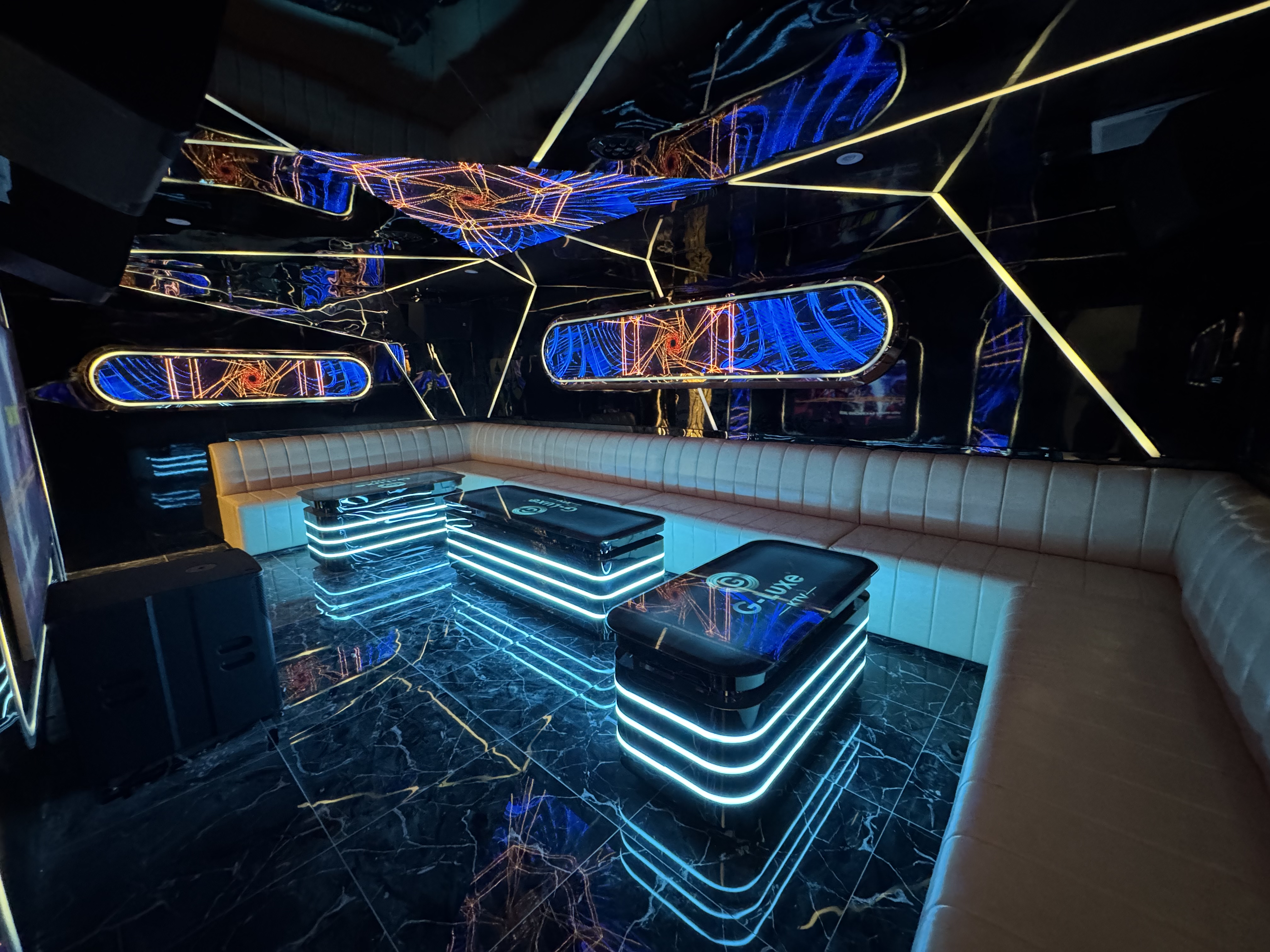 This is a nightclub interior with modern decor, lit seating, and abstract graphics on the walls.